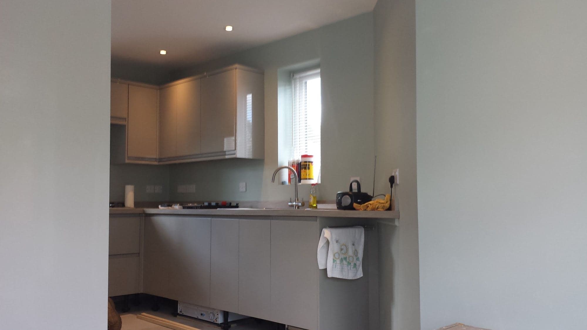 A kitchen with grey units and a hob fitted along one wall, with a window beside them