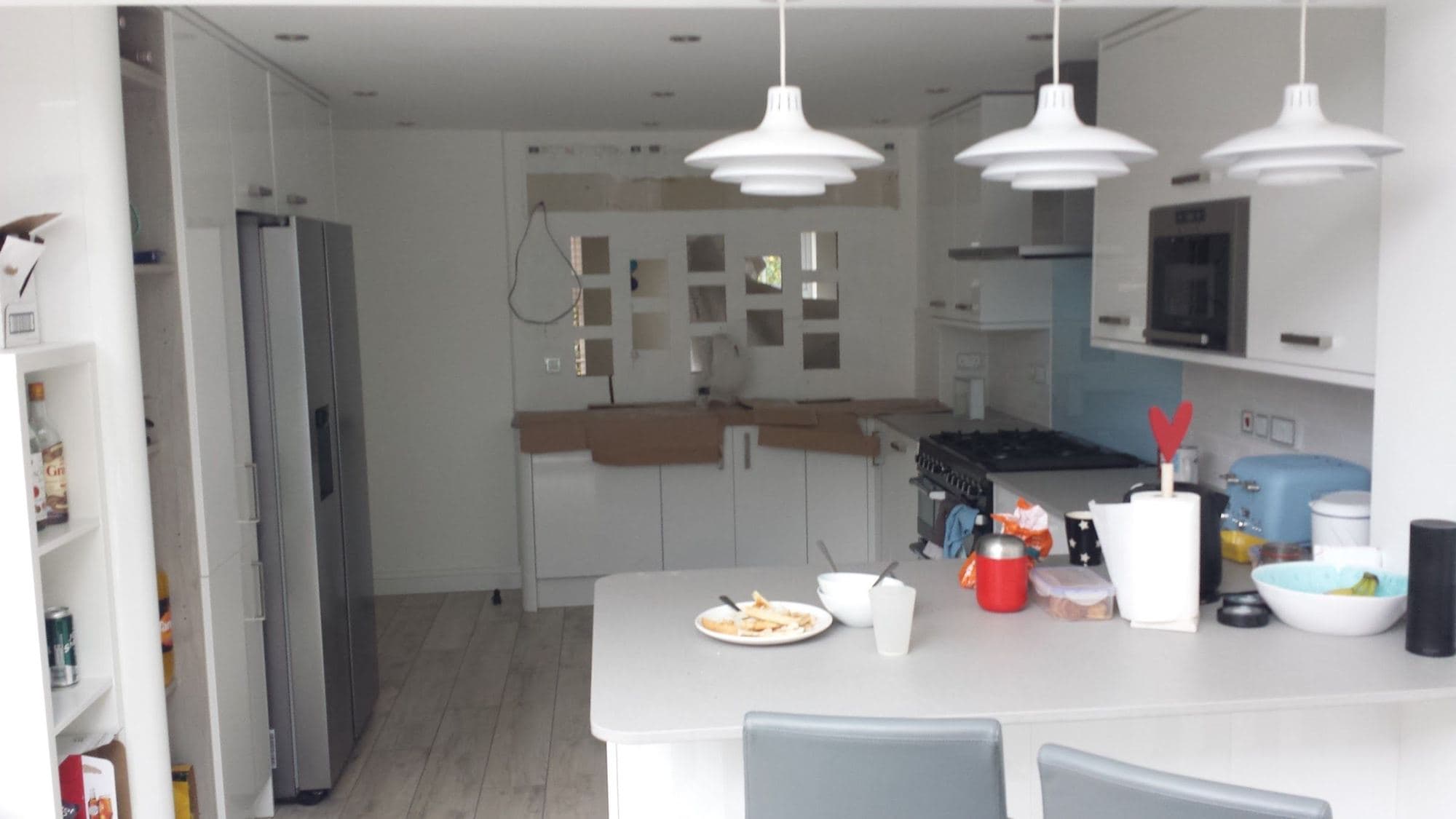 A kitchen diner with white units, a breakfast island and three pendant lights