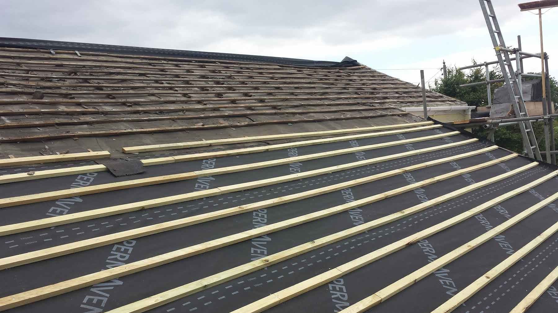 A roof stripped back and re-battened over breathable membrane, with a ladder and scaffold at the eaves