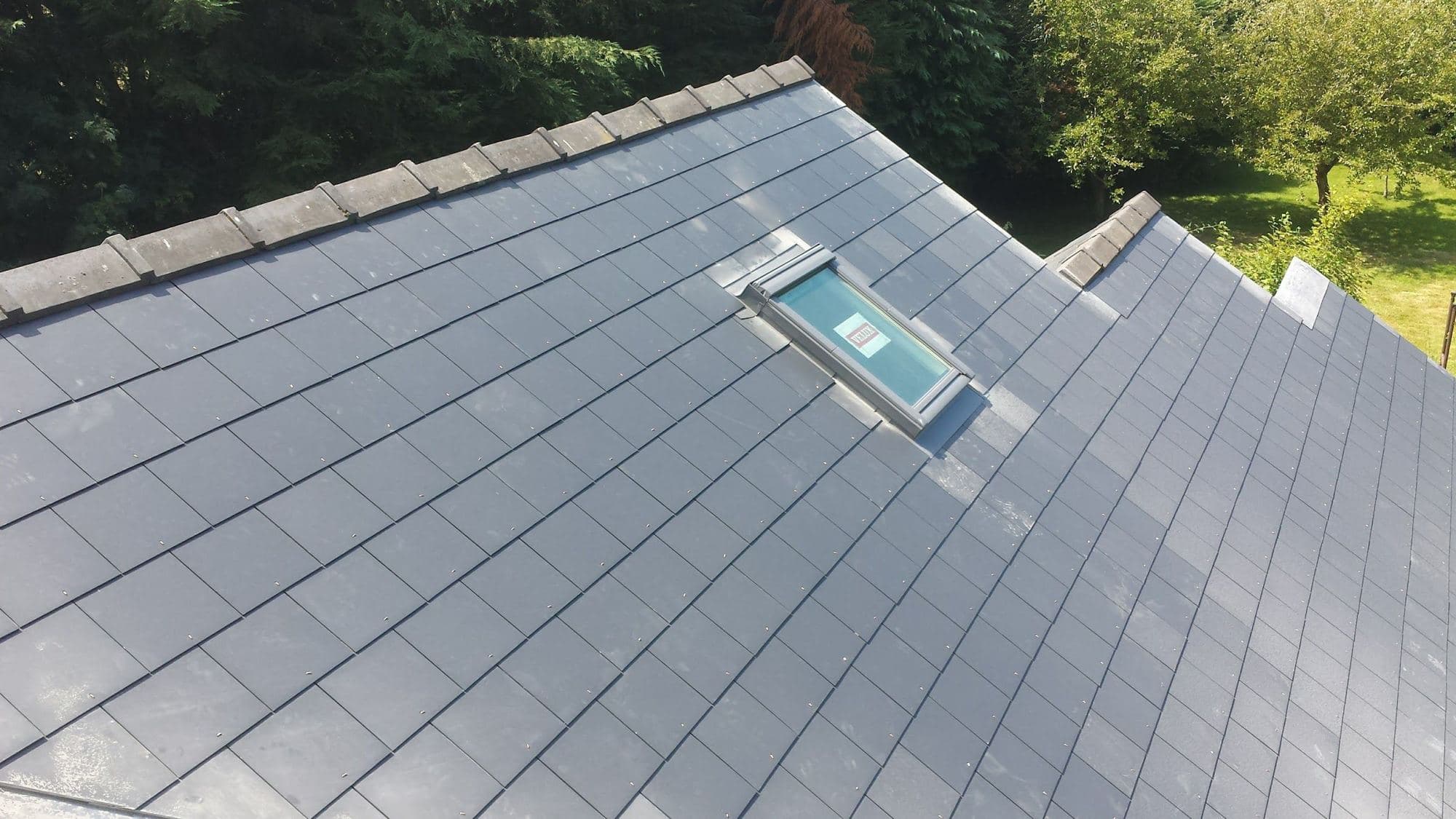 A new grey slate roof with a roof window set into it