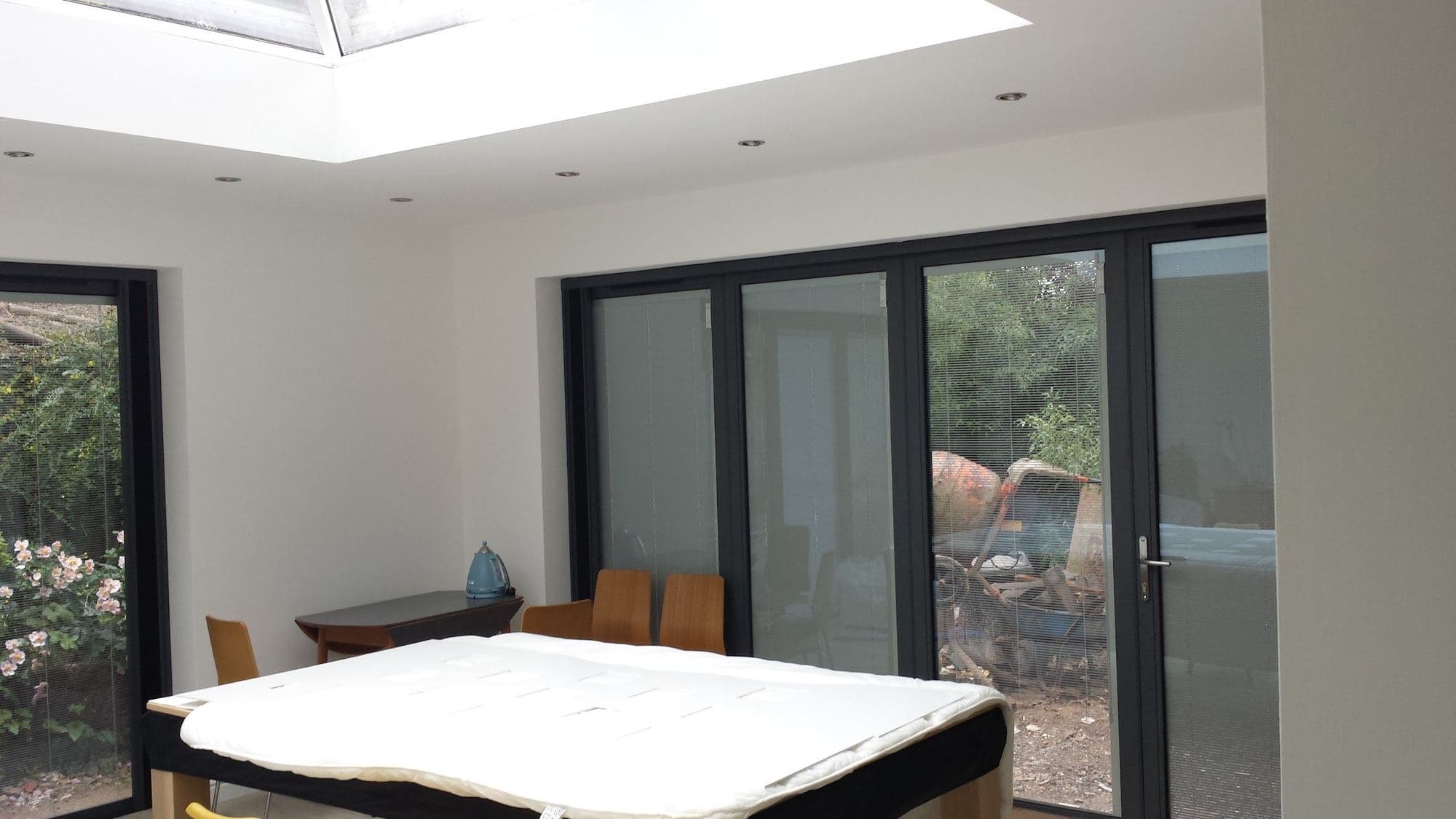 A new extension room with a roof lantern overhead and dark-framed bifold doors onto a garden