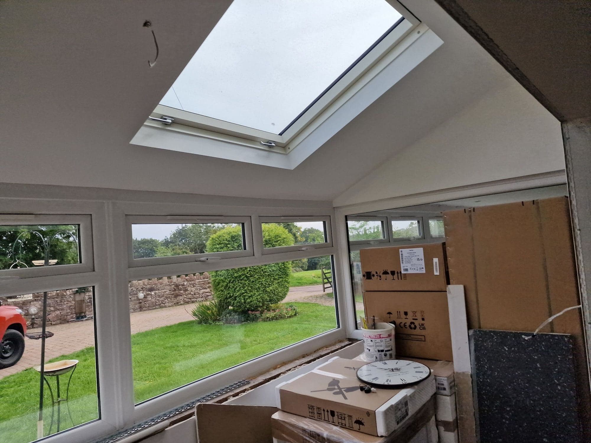 A new extension interior with a roof window overhead and new white windows looking onto a garden